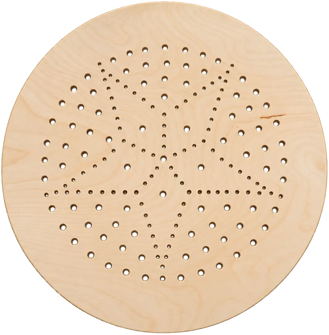 Casa. A round table seen from above. The top is pale wood with a soft figure, pierced by a pattern of small round holes that spirals out from the centre.