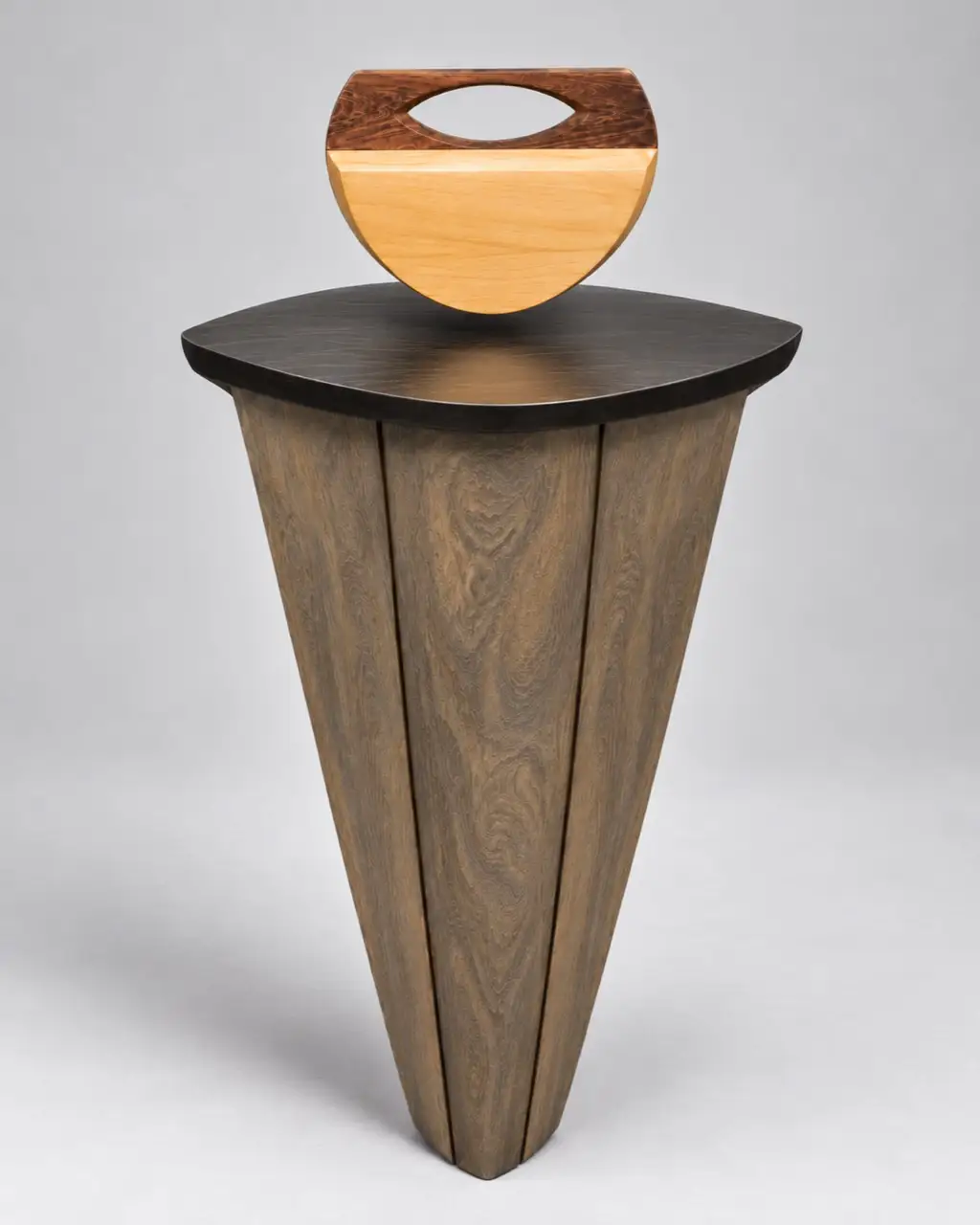 Culla d'Ombra. A half-round pale body under a dark figured cap with an oval opening. The wooden pedestal in the photograph is a display stand, not part of the piece.