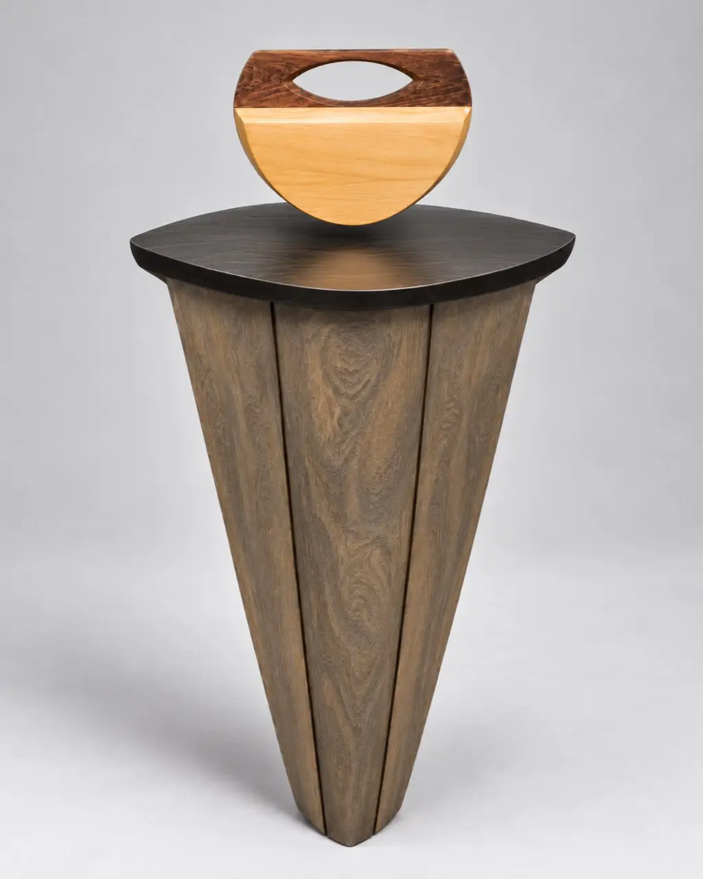 Culla d'Ombra. A half-round pale body under a dark figured cap with an oval opening. The wooden pedestal in the photograph is a display stand, not part of the piece.